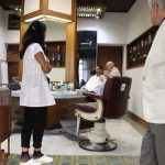 A barber inside the shop working on client's hair.