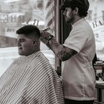 A barber inside the shop working on client's hair.