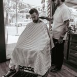 A barber inside the shop working on client's hair.