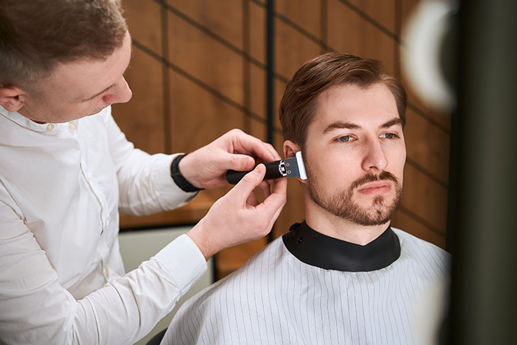 Close-up of barber detailing sideburns during a Visagism haircut